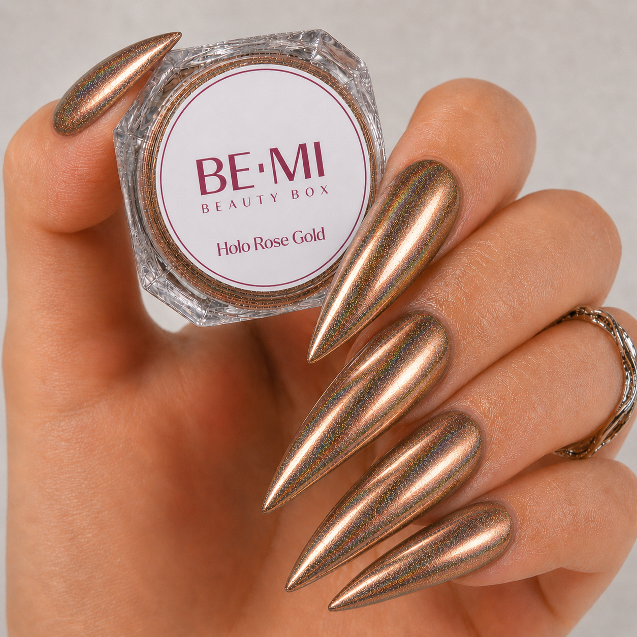 Finished manicured nails with a high-shine liquid metal effect using BEMI Chrome in Rose Gold Holo, burnished flawlessly over a gel base for professional nail artistry.