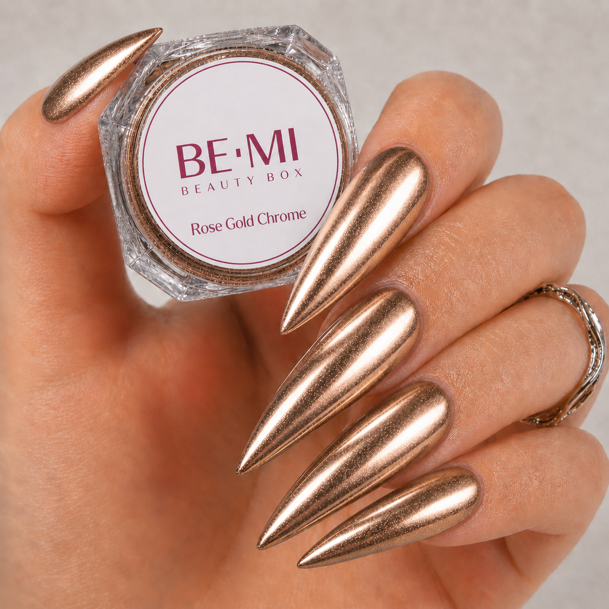 Finished manicured nails with a high-shine liquid metal effect using BEMI Chrome in Rose Gold, burnished flawlessly over a gel base for professional nail artistry.