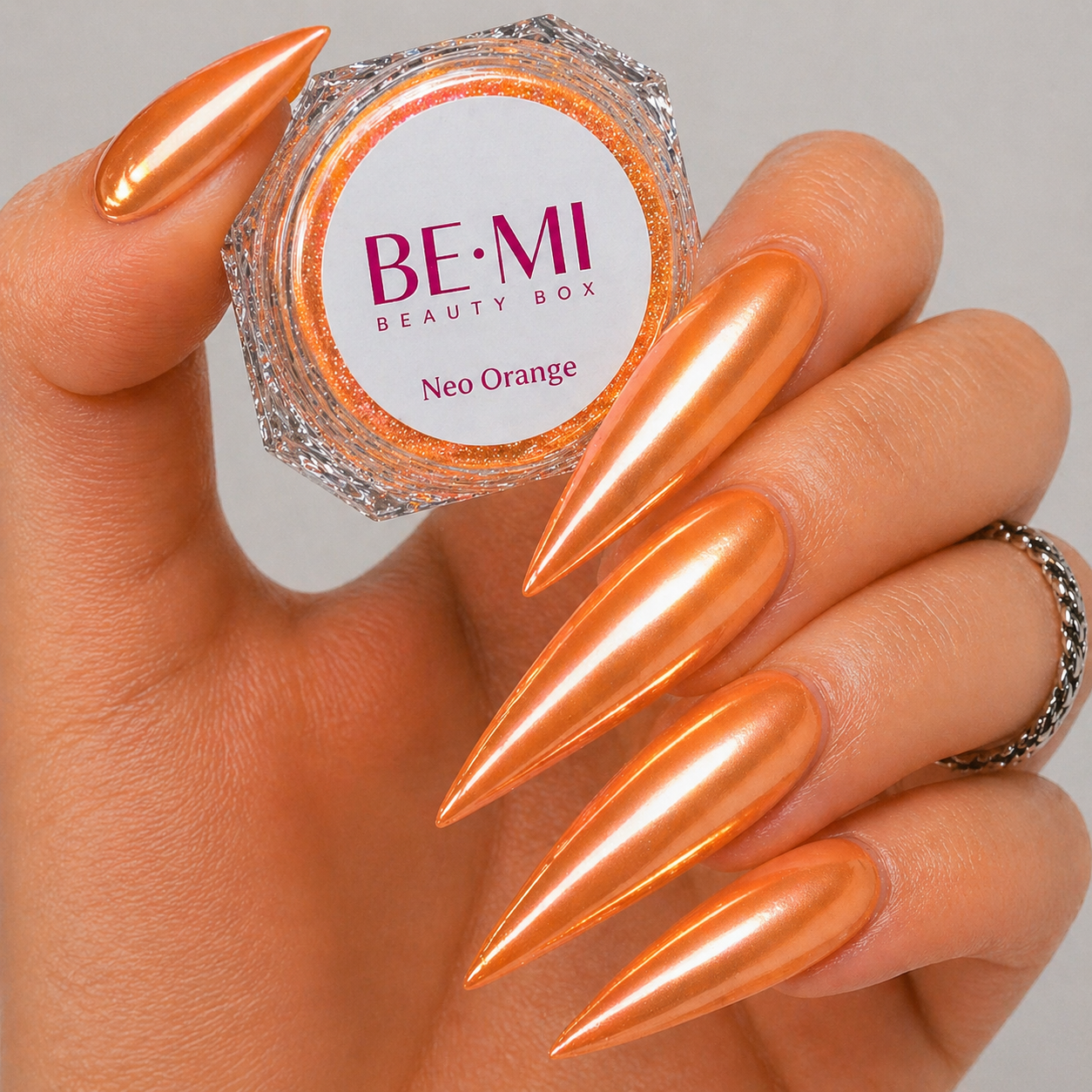 Finished manicured nails with a high-shine liquid metal effect using BEMI Chrome in Neo Orange, burnished flawlessly over a gel base for professional nail artistry.