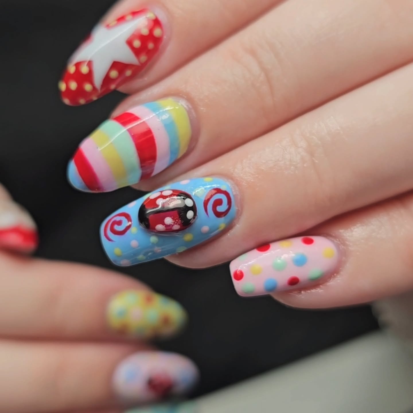 Bright rainbow stripes, stars, dots and ladybug nail art