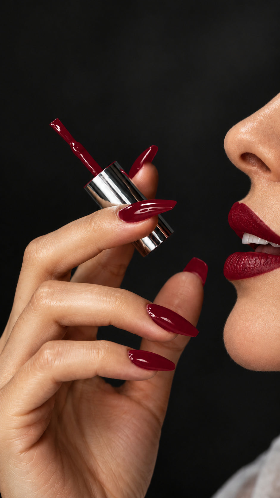 Close-up of a woman holding a silver gel-brush cap beside her face, with matching glossy nails, lips and brush gel in Roulette, BEMI R04.